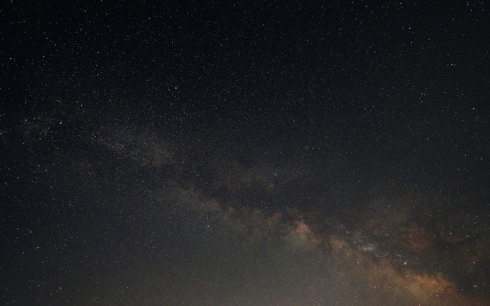 Dense star field with the Milky Way's cloudy band stretching diagonally across a dark night sky